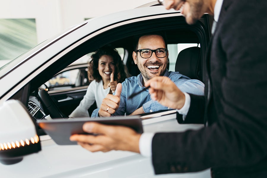 Woman and man sitting in a car at a dealership